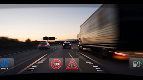 Point of view from the driver seat of a software-defined vehicle with a HUD display on the windshield while driving down busy highway.